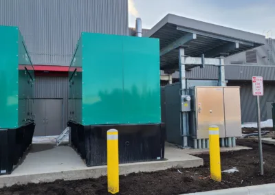 Two green generators in front of a building.